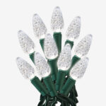 Close-up of Sylvania C6 warm white LED Christmas light bulbs on a green wire strand