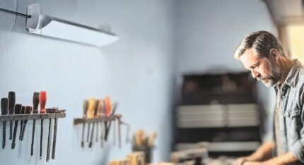 KODA 10,000-lumen adjustable LED shop light illuminating a workshop workbench